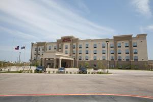 ein großes Gebäude mit Autos auf einem Parkplatz in der Unterkunft Hampton Inn & Suites Dallas I-30 Cockrell Hill, Tx in Dallas