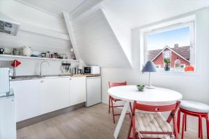 a kitchen with white cabinets and a table with red chairs at Grand Villa Stavanger in Stavanger