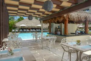 a restaurant with a pool and tables and chairs at Privilege Aluxes Adults Only in Isla Mujeres