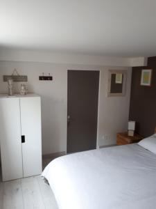 a bedroom with a white bed and a white cabinet at Le cosy plage in Ouistreham