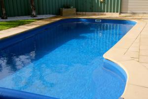a swimming pool with blue water in a yard at Lure Bed and Breakfast in Normanville