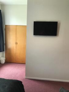 a flat screen tv on the wall of a bedroom at Criterion Club Hotel in Alexandra