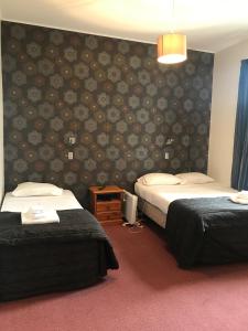 a hotel room with two beds and a wall with flowers at Criterion Club Hotel in Alexandra