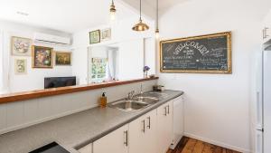 a kitchen with a sink and a chalkboard on the wall at The Vintage Cottage in Oneroa