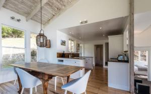 cocina y comedor con mesa de madera y sillas en Circular Bay en Awaroa