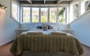 a bedroom with a large bed with two windows at Circular Bay in Awaroa
