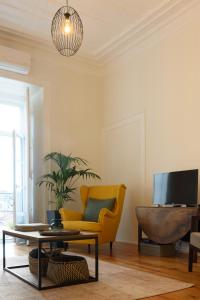 a living room with a yellow chair and a tv at Janelas Verdes Apartments in Lisbon