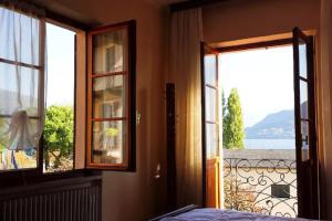 una camera da letto con due finestre e vista su un balcone di Casa Farfalla a Cannobio