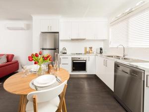 a kitchen with a wooden table and a kitchen with white cabinets at Understated Elegance Affordable Luxury in Albury