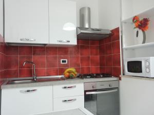 a kitchen with white cabinets and red tiles at Appartamento Tulipano Rosso in Trapani