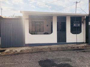 a small white house with a fence at Duerme tranquilo in Alajuela