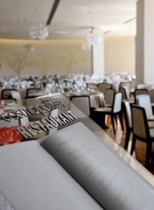 チヴィタノーヴァ・マルケにあるCosmopolitan Hotelのテーブルと椅子が備わる部屋のテーブルに書かれた本