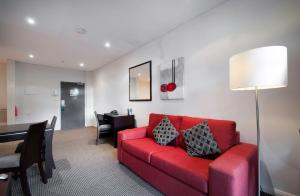 ein Wohnzimmer mit einem roten Sofa und einem Tisch in der Unterkunft Quest Canberra in Canberra