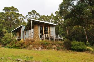 a small house on a hill with a grass field at Peppermint Ridge Retreat in Woodbridge