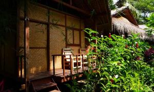 a porch of a house with a table and chairs at Shibui Garden Bungalows and Restaurant in Tanjung