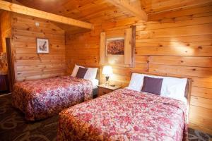 a bedroom with two beds in a log cabin at Bryce Gateway inn Cabins in Panguitch