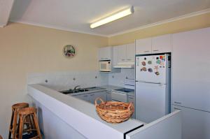 a kitchen with white cabinets and a white refrigerator at Bright & comfortable in quiet location in Sunshine Beach