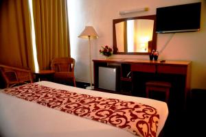 a hotel room with a bed and a desk and a mirror at Hotel Caliber in Kuala Lumpur