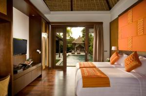 ein Schlafzimmer mit einem Bett, einem TV und einem Pool in der Unterkunft Mahagiri Villas Sanur in Sanur