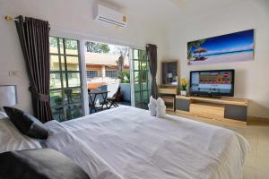 a bedroom with a large white bed and a television at Grande Adam Private Pool Villa in Pattaya Central