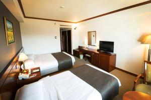 a hotel room with two beds and a desk and a television at Commodore Hotel Gyeongju in Gyeongju