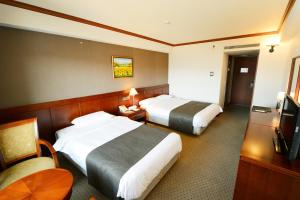 a hotel room with two beds and a television at Commodore Hotel Gyeongju in Gyeongju