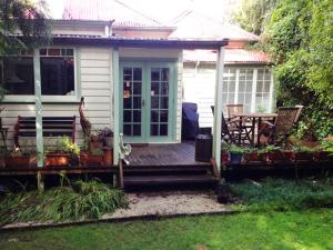 a house with a wooden porch with a table and chairs at Lemon Tree Cottage in Leura