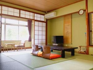 a living room with a wooden table and chairs at Hotel Yumoto in Utsuno