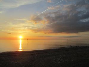 a sunset on the beach with the sun setting at Gate Lodge Guest House in Hunstanton