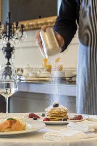 a person sprinkling powdered sugar on a stack of pancakes at 3 Sixty Hotel & Suites in Nafplio