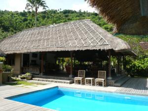 a resort with a swimming pool and a thatch roof at Le Jardin in Amed +9 photos