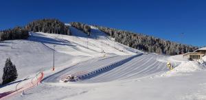une piste de ski couverte de neige avec des personnes qui la descendent dans l'établissement Kapriol, à Castello Tesino