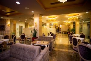 un restaurante con sofás, mesas y sillas en Hotel Colosseo & Spa, en Shkodër