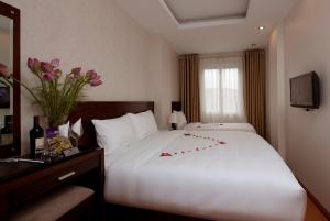 una habitación de hotel con una gran cama blanca con flores. en Rising Dragon Legend Hotel en Hanói