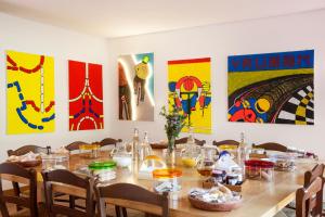a long table with chairs and paintings on the wall at Il Locandiere in Capitana