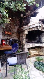 a patio with a table and chairs and a stone fireplace at Apartman i Sobe Čule Cres in Cres
