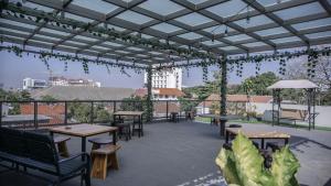 a patio with tables and chairs on a roof at Mogens Guesthouse in Bandung