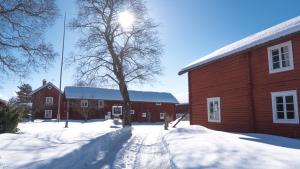 Czerwona stodoła w śniegu obok budynku w obiekcie Wikgården B&B w mieście Gagnef