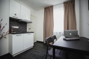 Una cocina con una mesa con una computadora portátil encima. en Aparthotel Messe Laatzen, en Hannover