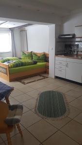 ein Wohnzimmer mit einem grünen Bett und eine Küche in der Unterkunft Harz Stolberg Ferienwohnung in Stolberg i. Harz