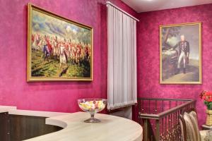 a dining room with pink walls and a painting on the wall at Suvorovskaya Hotel in Moscow