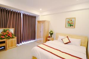 Schlafzimmer mit einem Bett und einem Fenster mit Vorhängen in der Unterkunft Mai Hoang Da Lat Hotel in Da Lat