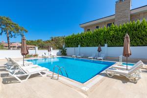 a swimming pool with lounge chairs and umbrellas at Forest Park Hotel in Kemer