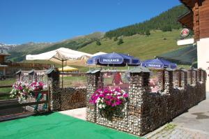 a garden area with flowers and umbrellas at Hotel Carpe Diem in Livigno