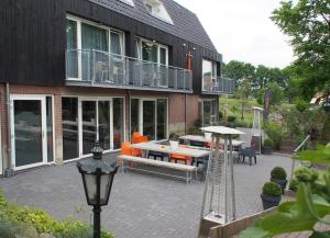 een patio met een tafel en stoelen en een gebouw bij Villavelo Twente in Ootmarsum