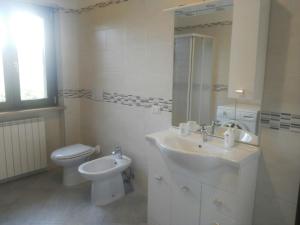 uma casa de banho com um lavatório, um WC e um espelho. em Casale di Burano em Onano