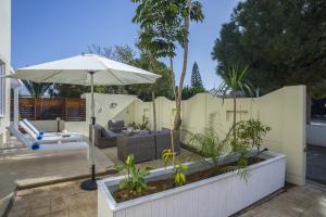a patio with an umbrella and a couch and a chair at Villa Mylos 8 in Protaras