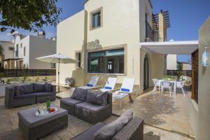 een patio met banken en stoelen en een tafel bij Villa Mylos 8 in Protaras