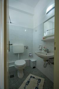 a white bathroom with a toilet and a sink at Sunrise Hotel in Ios Chora