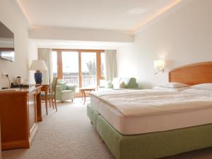 a hotel room with a bed and a desk and chairs at ALPIN- Das Sporthotel - SKI IN SKI OUT cityXpress, SUMMERCARD INCLUDED in Zell am See
